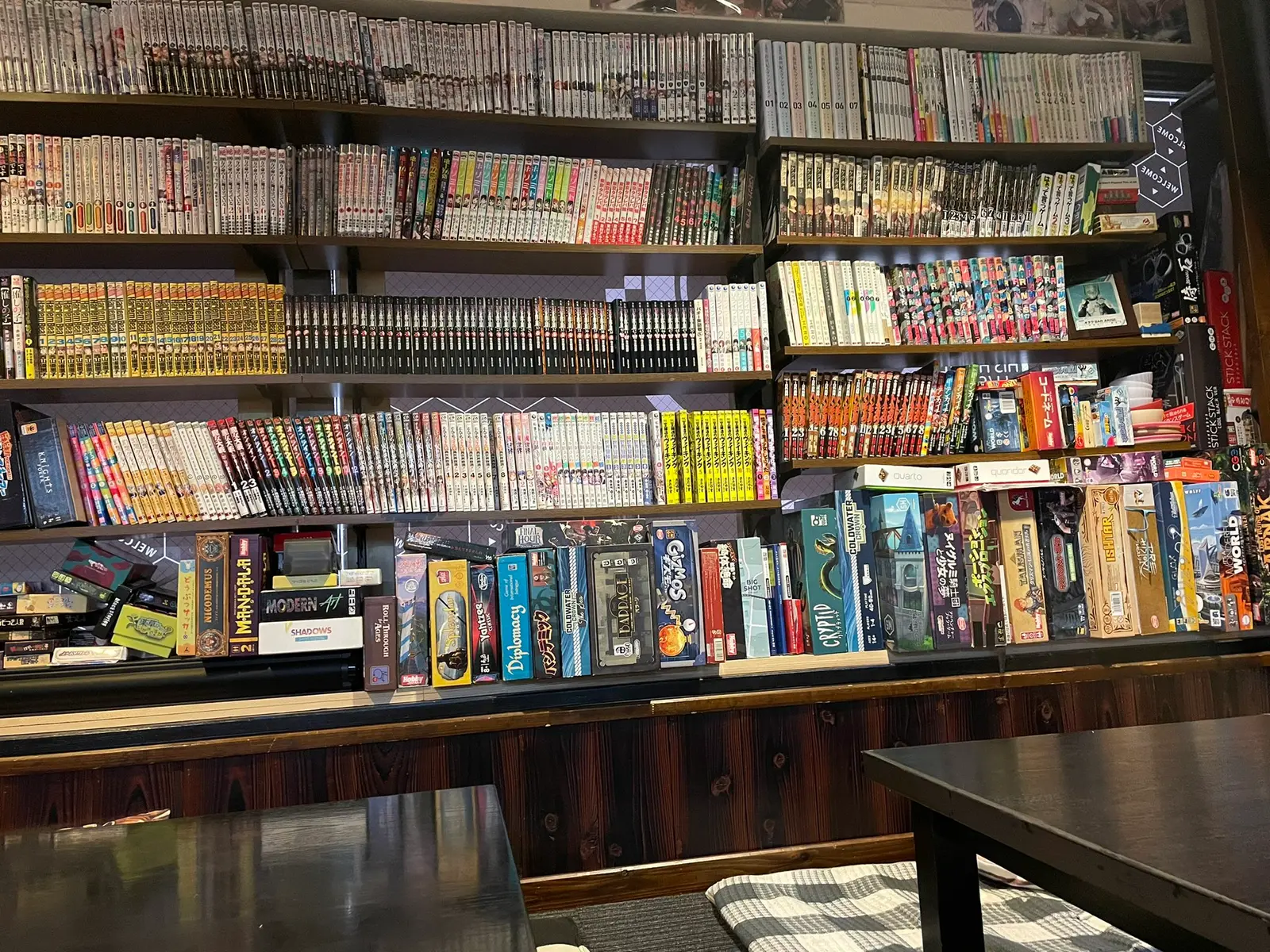 大きい棚にたくさんの漫画と下の方にはボードゲームも並べられている