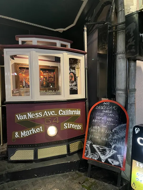 店名のモチーフとなったケーブルカーの前に、お酒のイラストと料金説明の書かれた立て看板